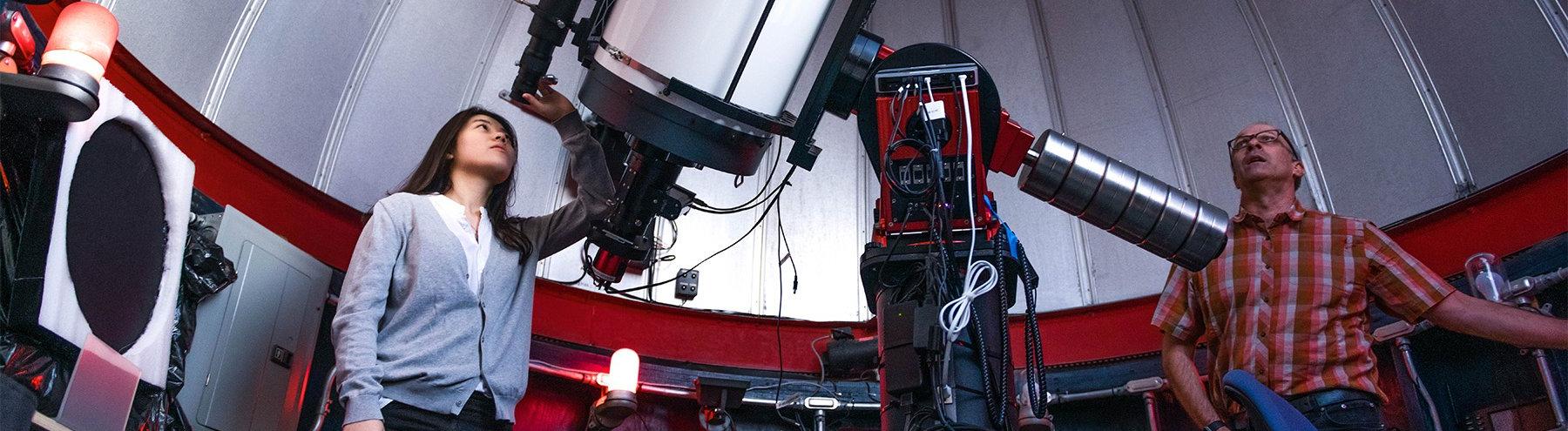 student looks through telescope